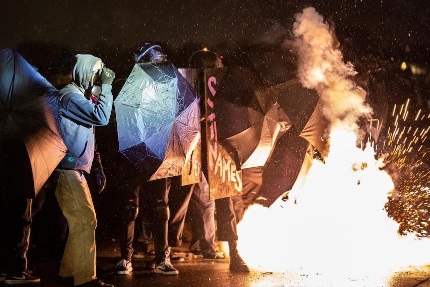 A crowd-dispersal canister explodes beside demonstrators gathered outside the Brooklyn Centre Police Department.