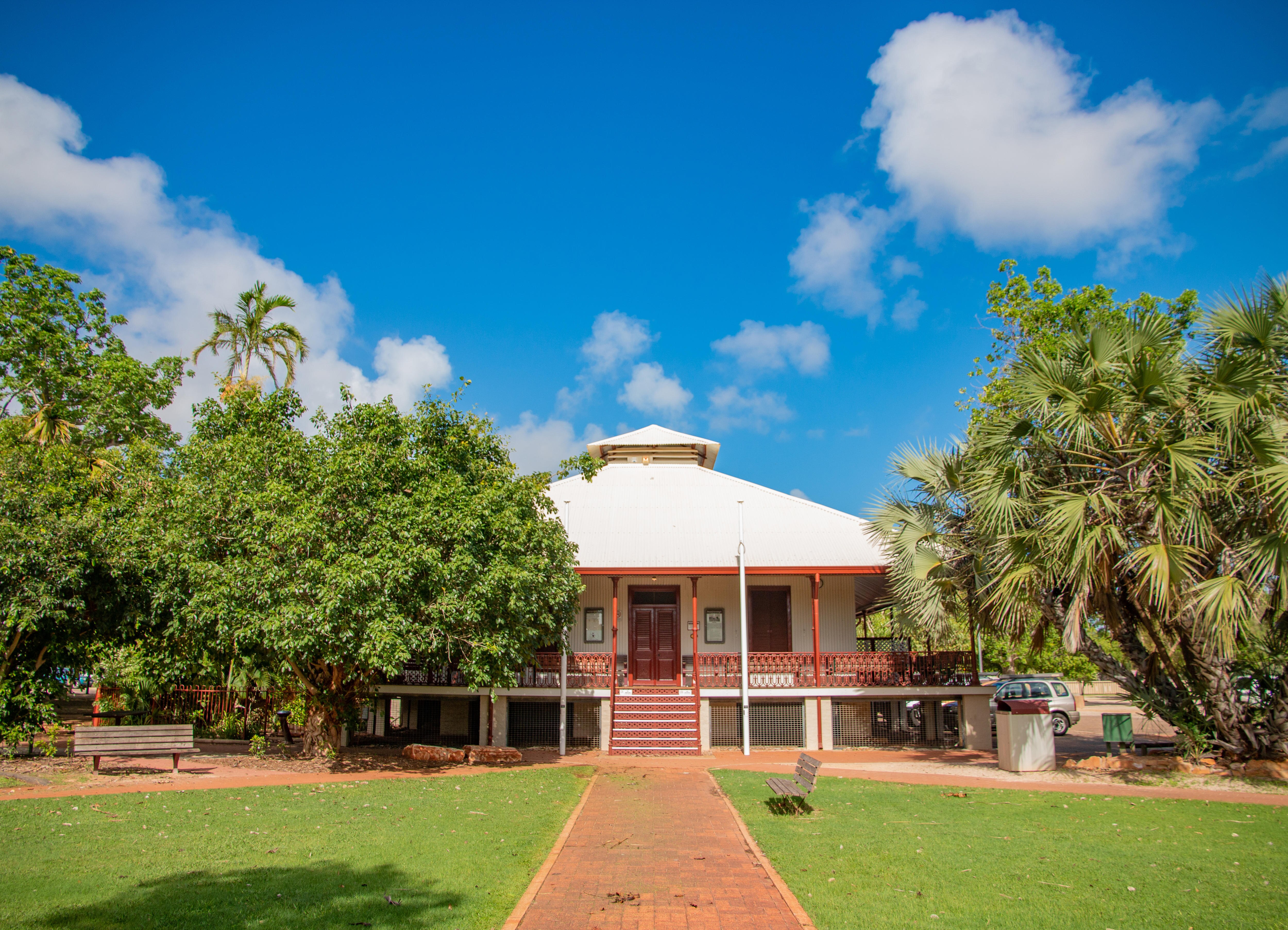 Green lawn and a straight path lead to steps to an old fashioned building
