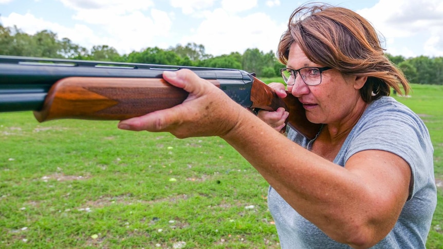 Deserie Baynes holds a gun on her shoulder and stares down the barrel ready to fire.