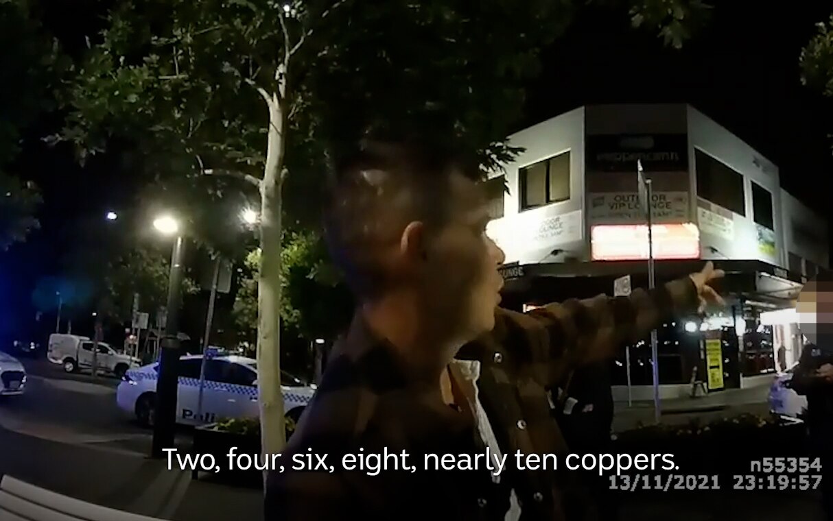 Body-worn camera footage of police talking to a man at night.