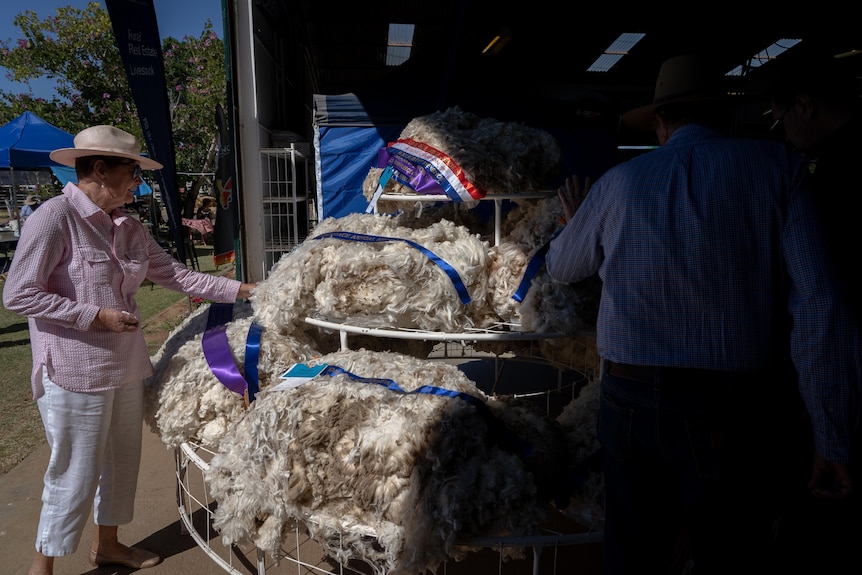 A woman touches wool fleeces piled up at a regional agricultural show.