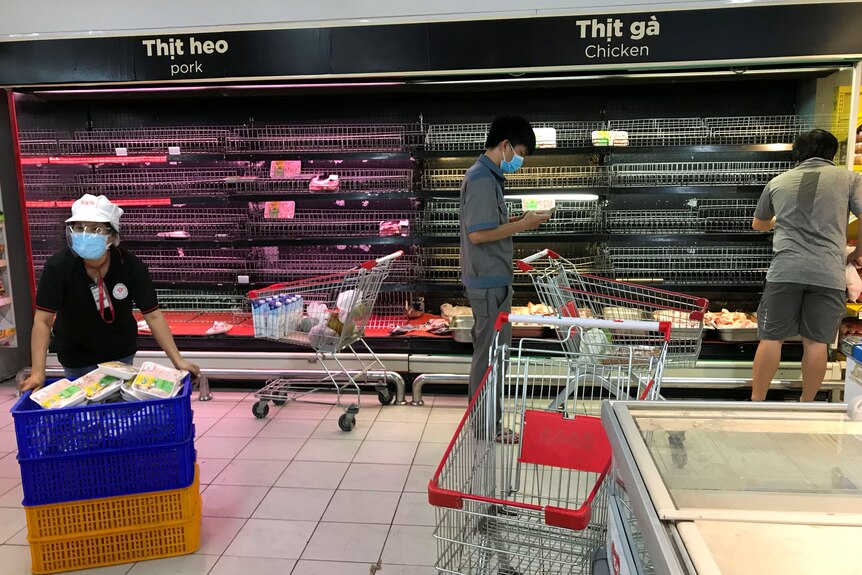 Customers search for food on near empty shelves that were depleted due to panic buying.