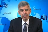 Close up shot of Mohamed El-Erian wearing a black suit and looking directly at camera, with a blue background