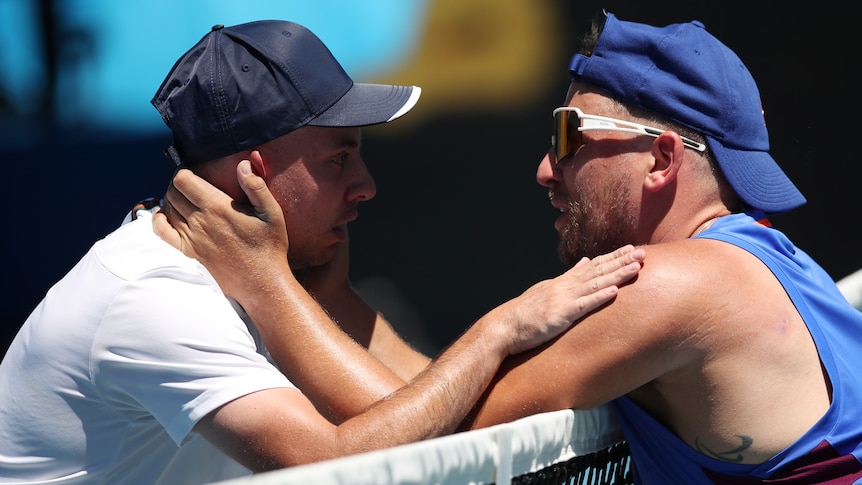 Two male tennis player embrace at the net after their quad wheelchair singles match at the Australian Open.