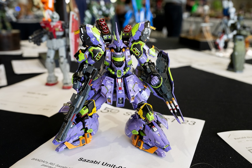 A model of a purple and green robot with weapons.