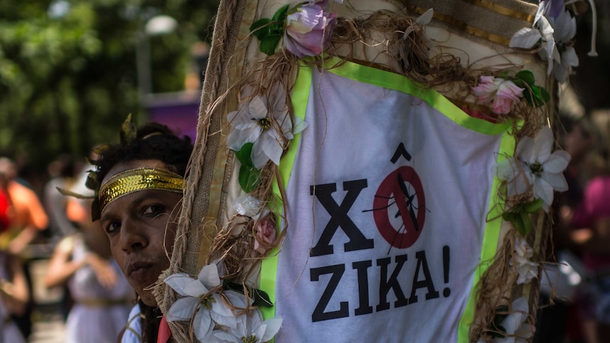 A man holds up a Zika virus sign on the streets of Rio.