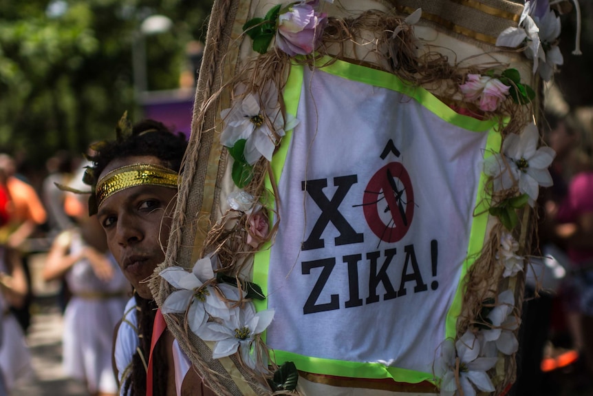 A man holds up a Zika virus sign on the streets of Rio.