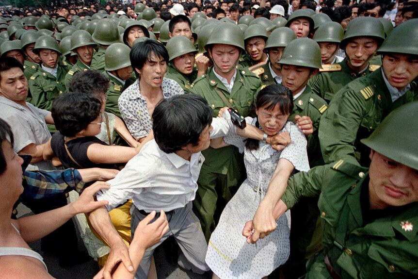 A young woman is caught between civilians and Chinese soldiers in Tiananmen Square on June 3, 1989.