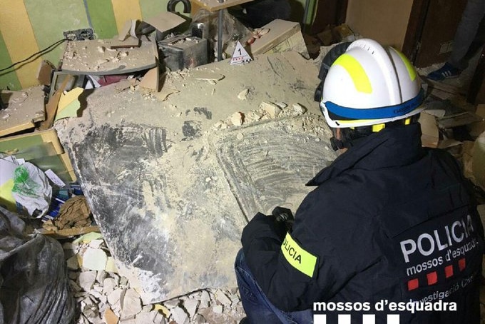 Police officer examines a large industrial metal sheet surrounded by debris, that crashed into a Spanish apartment killing a man