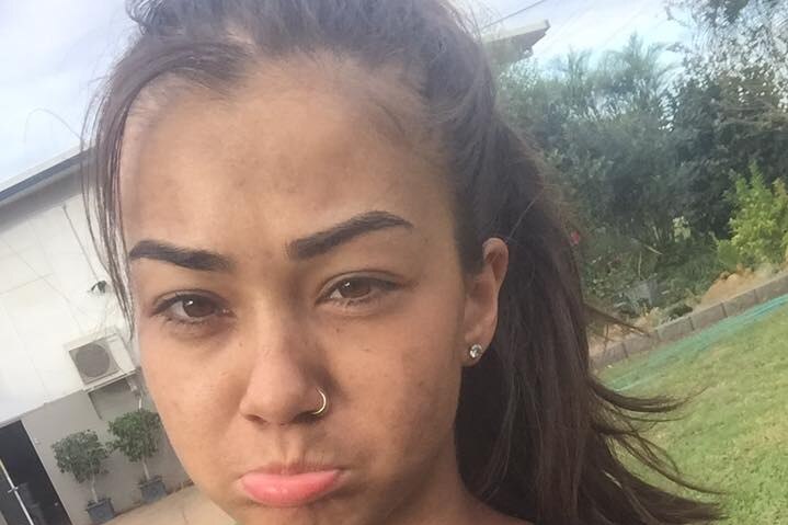 A young woman with dirt on her face poses for a selfie with a sad expression on her face