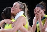Australian women's basketball players hug each other after losing their Tokyo Olympics quarter-final against USA.