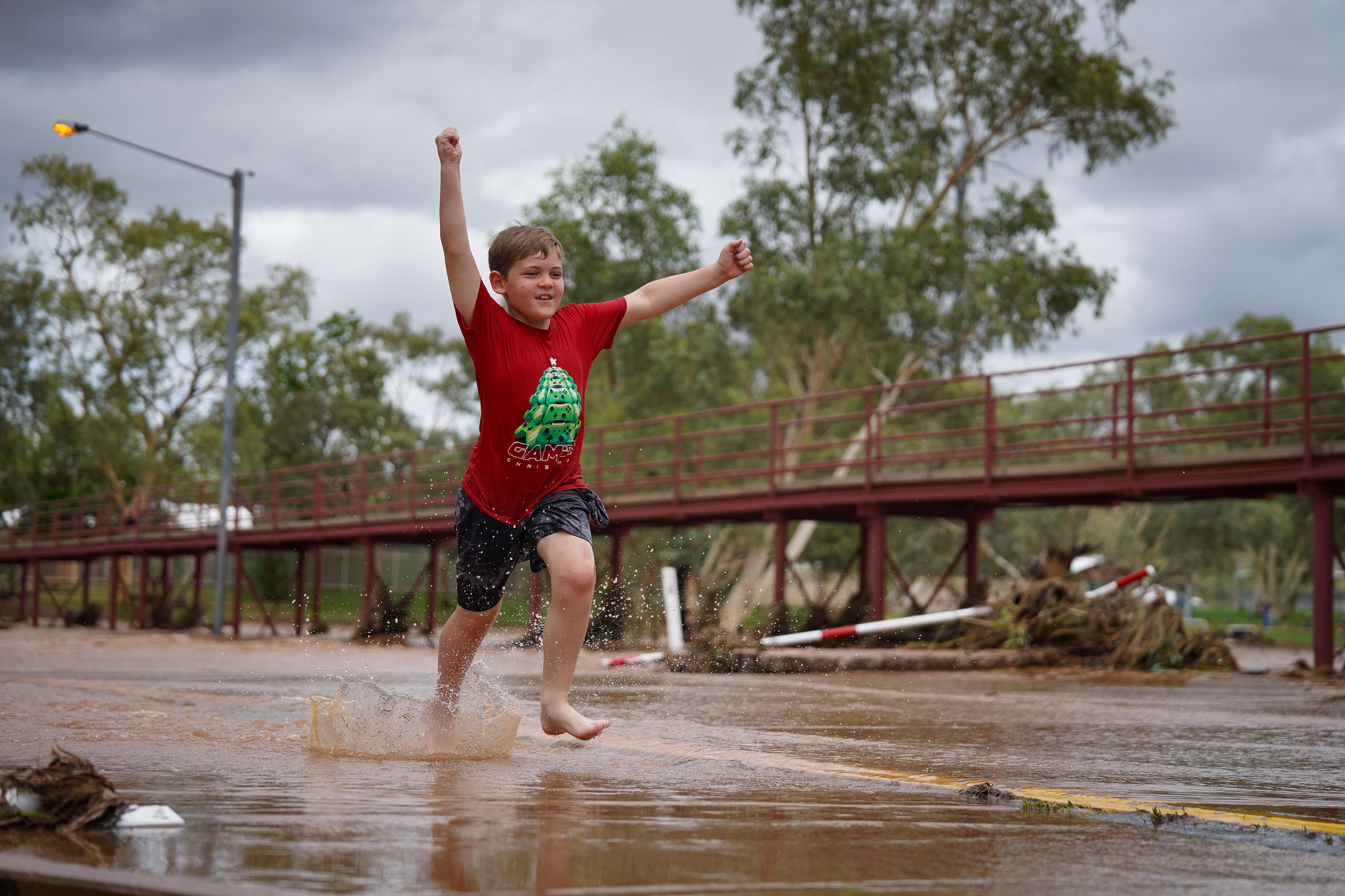Um menino com uma camiseta vermelha levantando água 