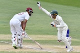Alex Carey runs past Roston Chase with his arm up