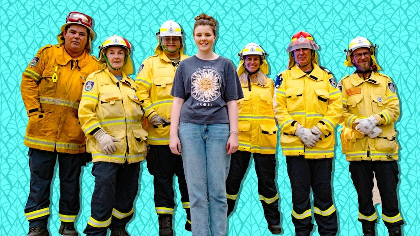 A girl in casual clothes stands with a group of firemen and women in full protective clothing.