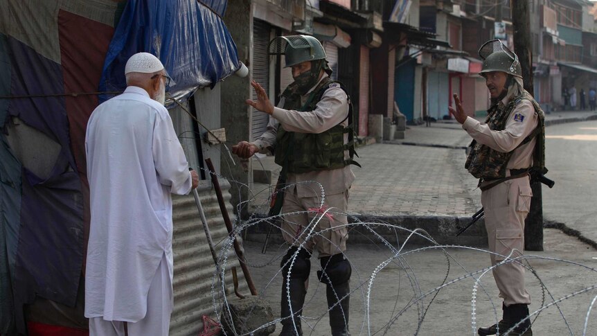 Old man dressed in white stopped by security forces near barbed wire