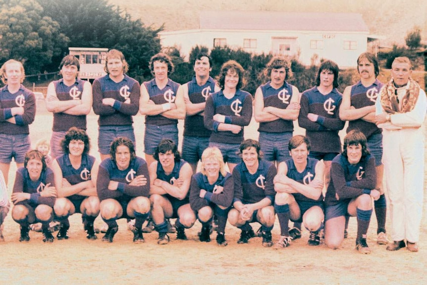 Faded colour photo of a football team posing for a team shot on a gravel oval