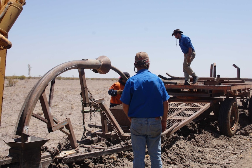 Workers turning up the soil to lay hundreds of metres of water pipe to transfer water across the property to troughs.