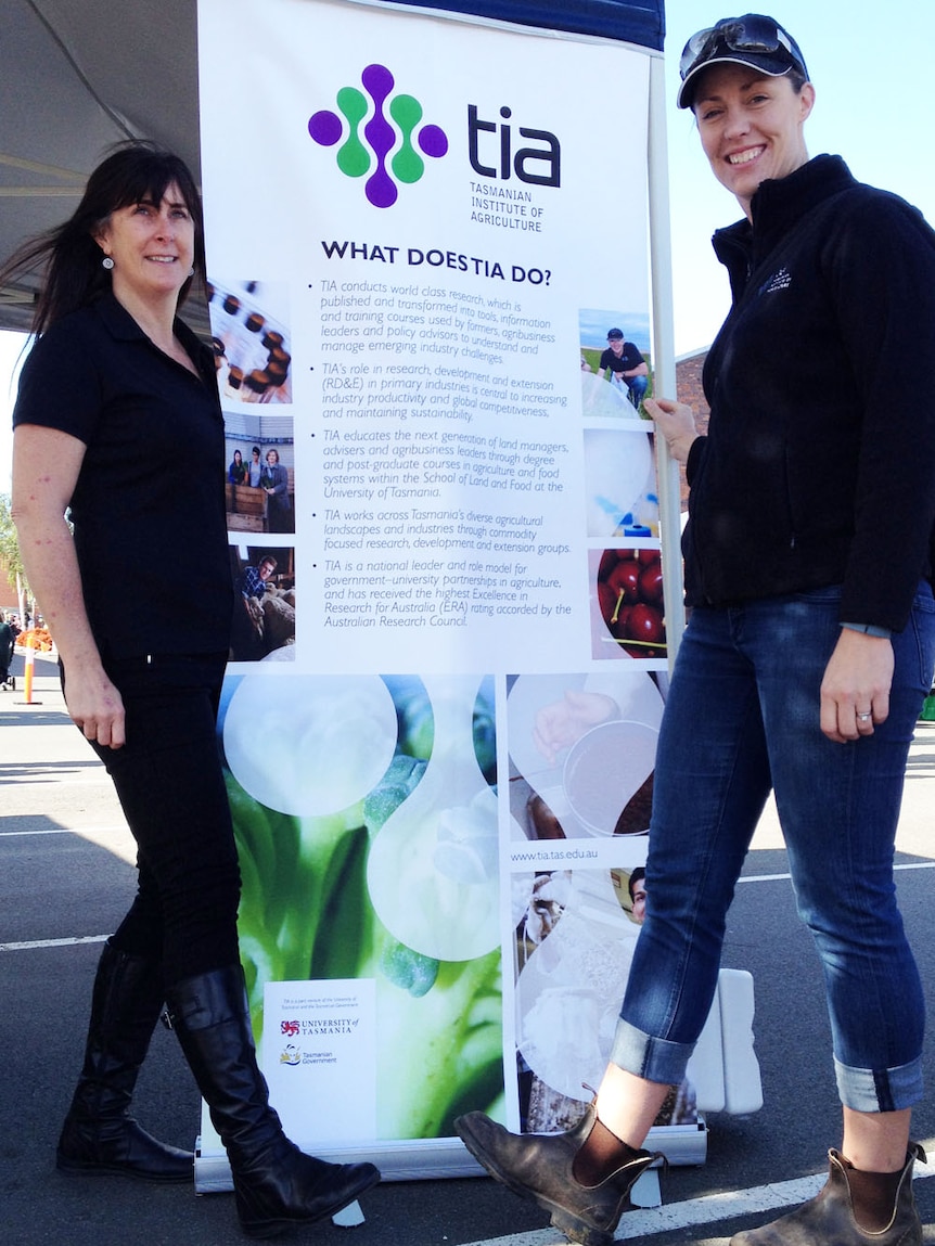 Dr Lyndal Mellefont and Dr Fiona Kerslake sporting boots in front of a Tasmanian Institute of Agriculture banner at the farmers