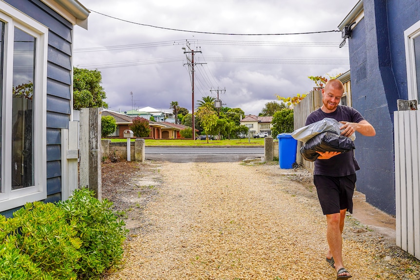 A man carries parcels as he walks between two buildings