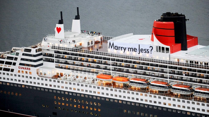 A Valentine's Day marriage proposal banner hangs off the side of the cruise ship Queen Mary 2