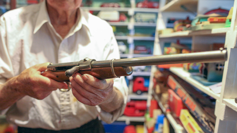 Jack Little holding a vintage wooden gun.