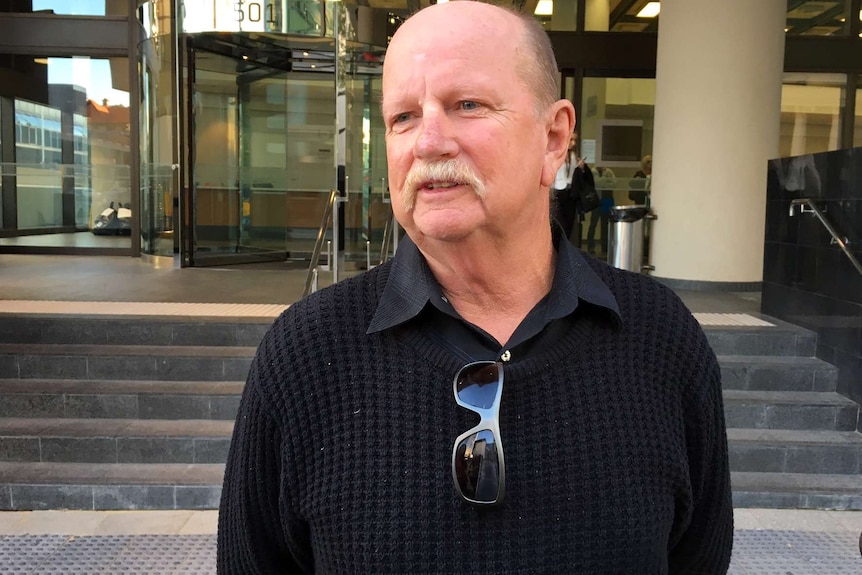 A mid shot of Damien Mills's father-in-law Jim Irvine wearing a black jumper and speaking outside a Perth court.