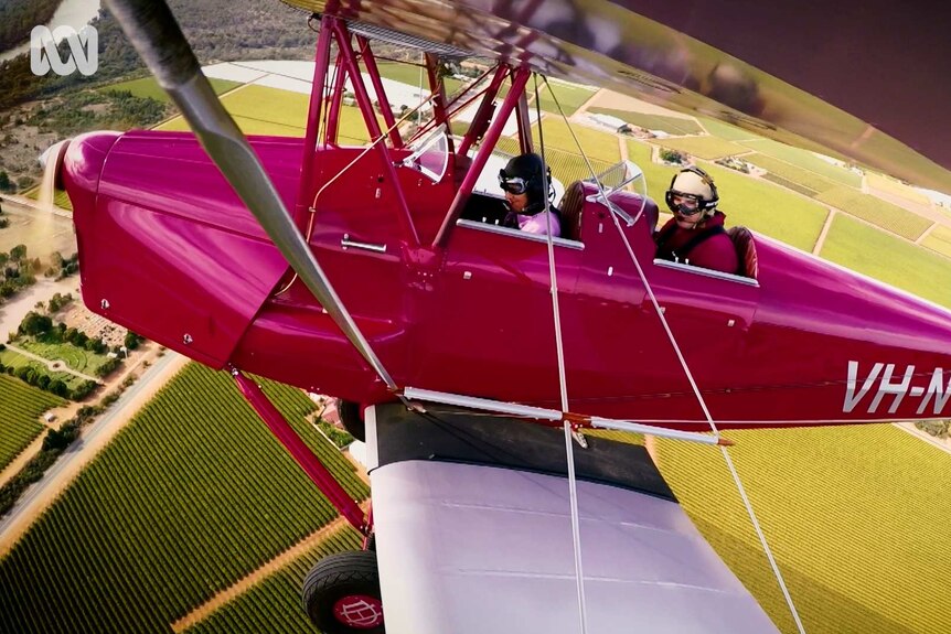 Two People sitting in red biplane