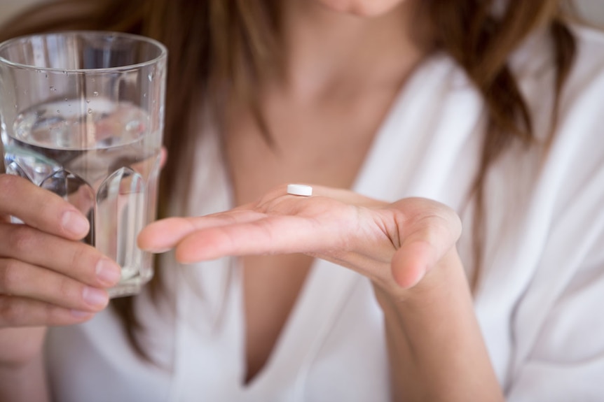 Woman holds a tablet with a glass of water.