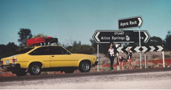 The Chamberlain family stand next to their Torana by the sign to Ayres Rock.