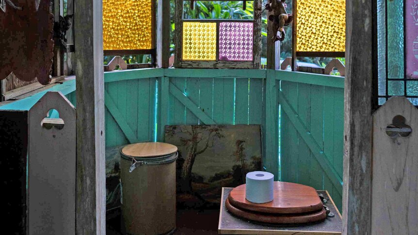 A timber room, featuring stained-glass windows, that houses a composting toilet.