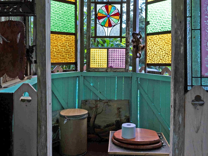 A timber room, featuring stained-glass windows, that houses a composting toilet.