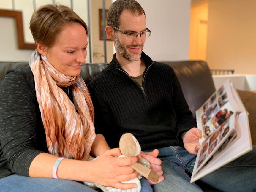 A woman and a man sitting and looking through a photo album.