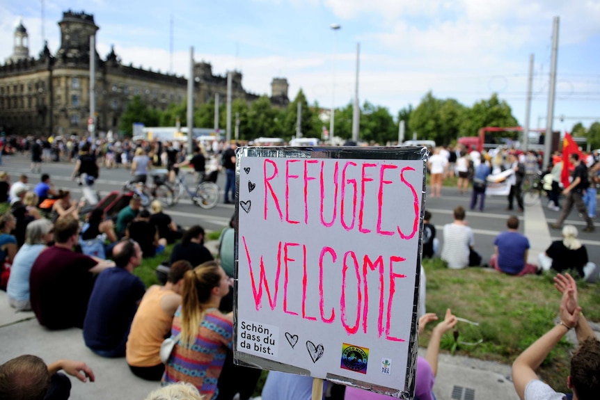 Anti-racism protesters sit behind a banner during a rally in Dresden