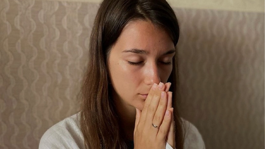  A woman holds her hands together in prayer
