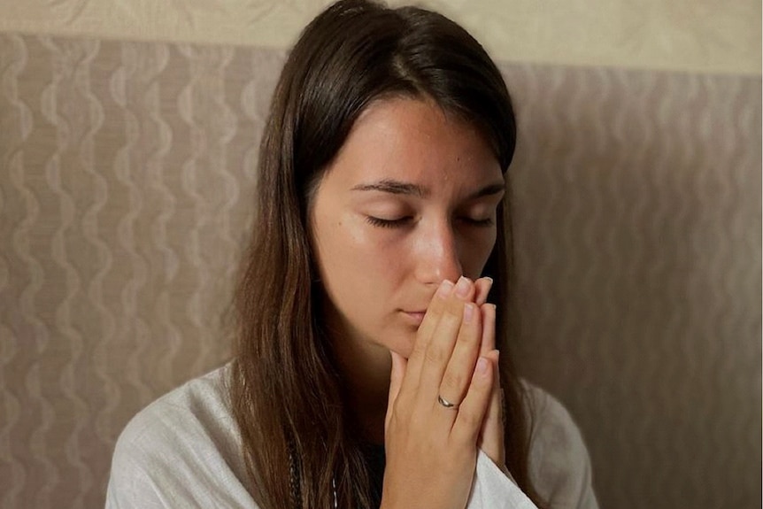  A woman holds her hands together in prayer