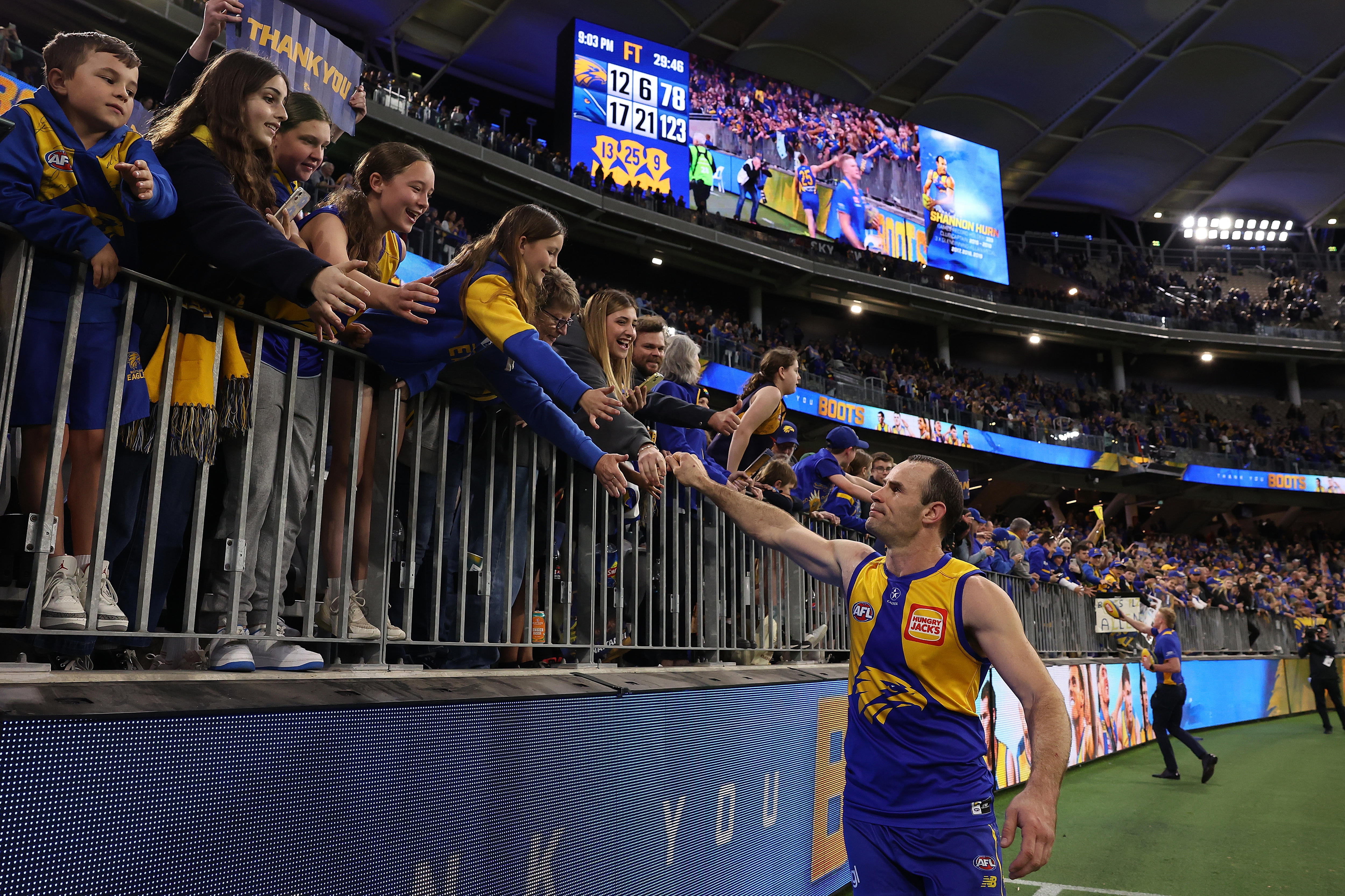 A retiring AFL player reaches up to shake the hands of West Coast fans after his final game.