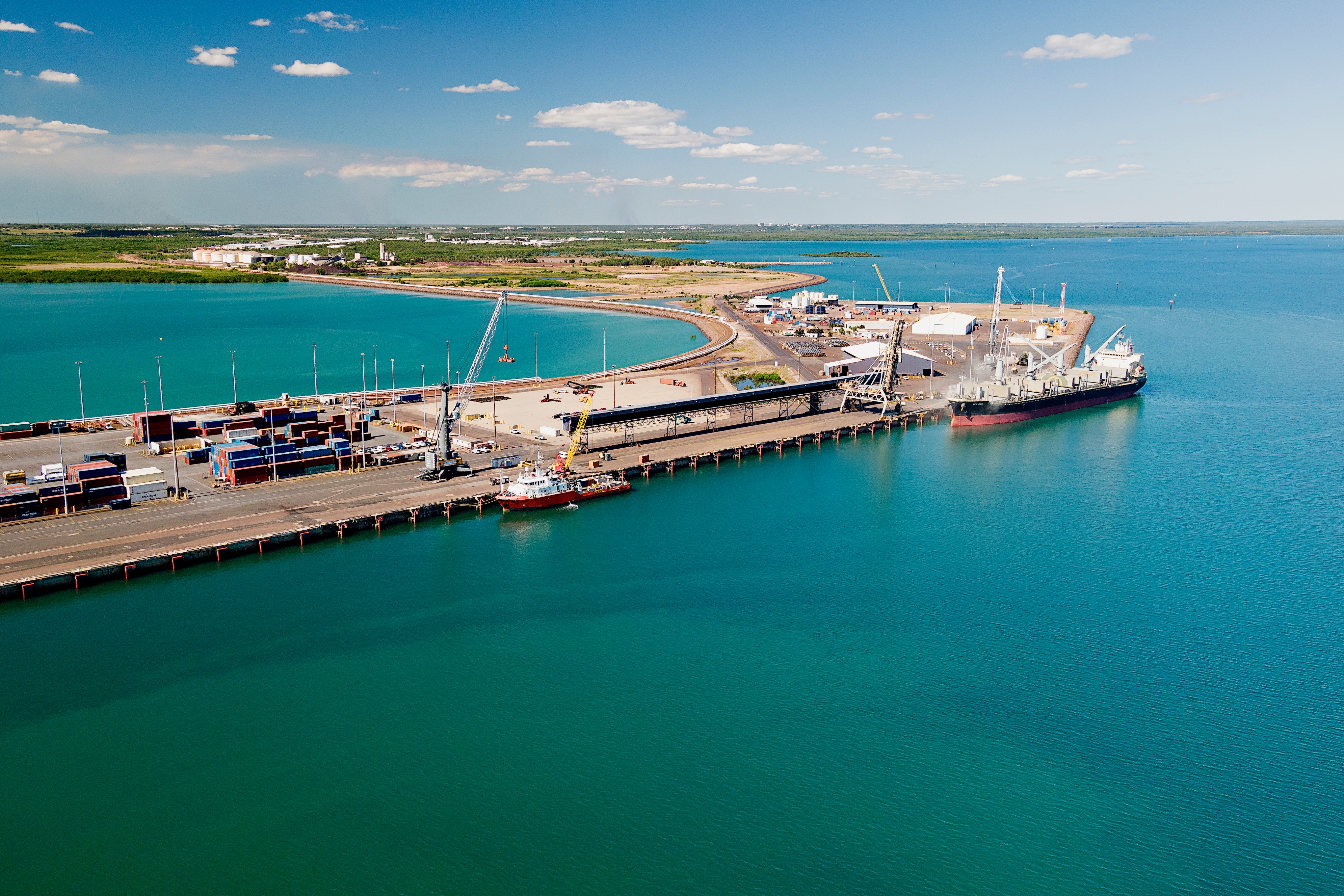 An aerial view of a wharf part of the Darwin Port, with the city of Darwin in the distance.