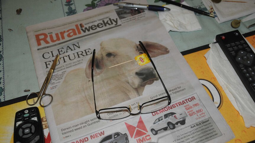 A pair of reading glasses and scissors on a copy of Rural Weekly.