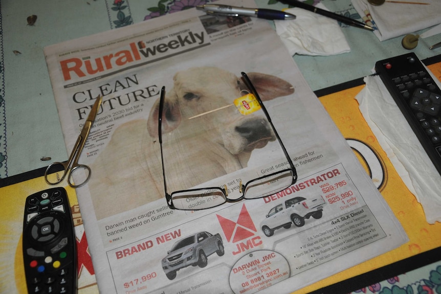 A pair of reading glasses and scissors on a copy of Rural Weekly.