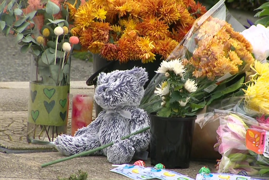 Flowers and a grey teddy bear