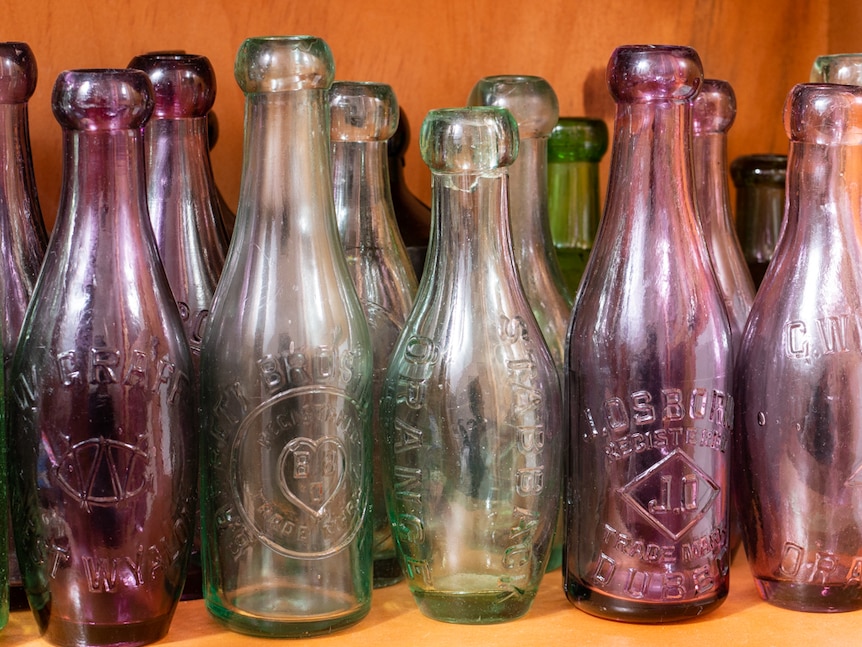 A collection of historic glass bottles in a display cabinet.