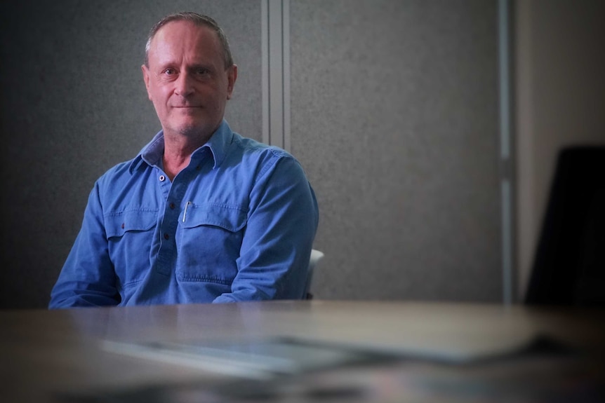 NT Labor MLA Jeff Collins stars at a camera in a dark room.