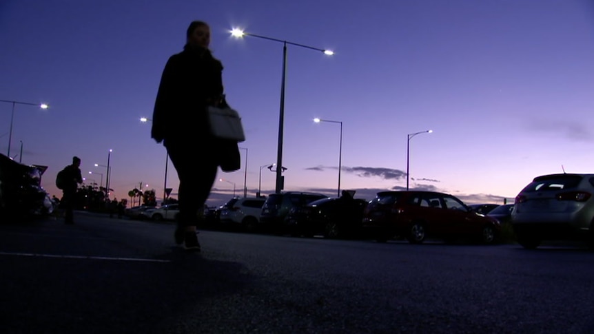 Silhouette of a woman in a car park with purple sky before sunrise