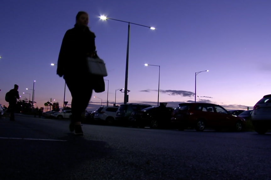 Silhouette of a woman in a car park with purple sky before sunrise