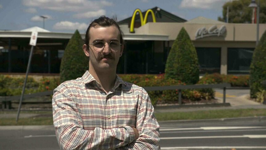 Former McDonald's employee, Max Beech, standing in front of a McDonalds
