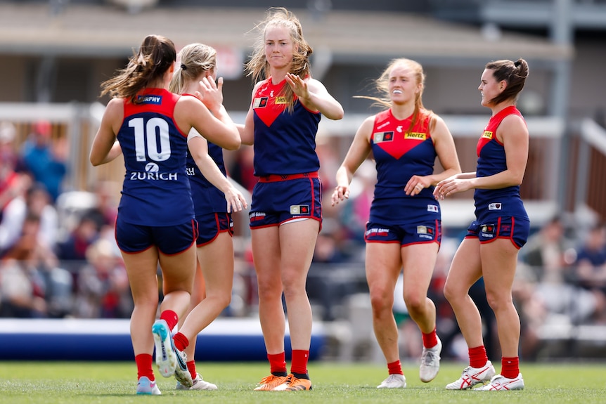 Melbourne AFLW players congratulate each other following a goal.