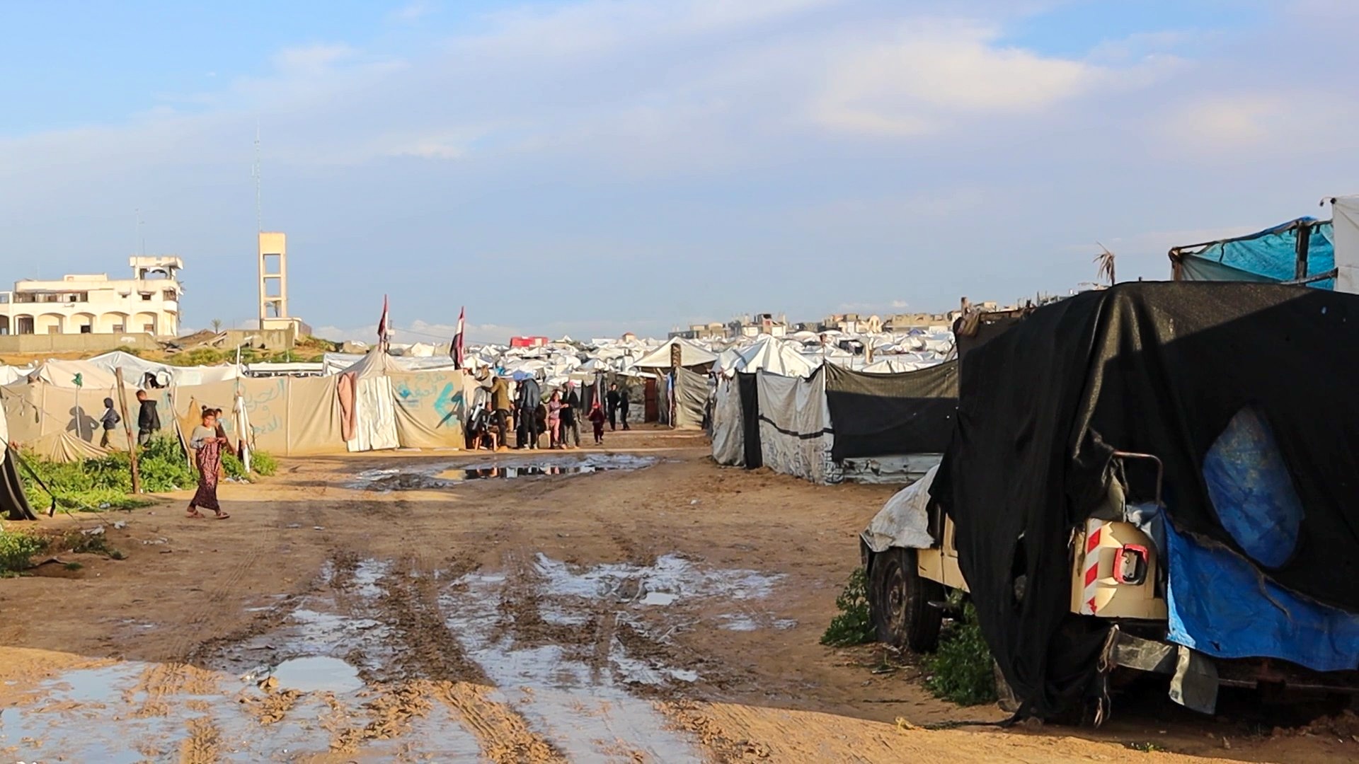 Dozens of make shift tents on muddy dirt ground.