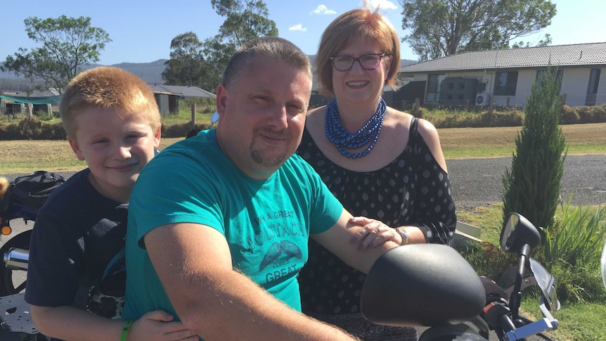 Bailey and his dad, Duncan, sit on a motorbike.