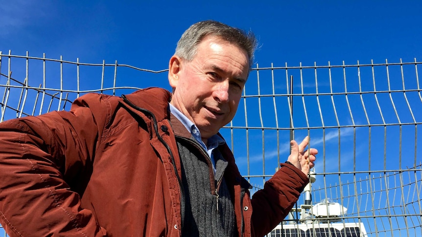 Peter Fraser stands in front of a solar panel.