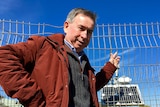 Peter Fraser stands in front of a solar panel.